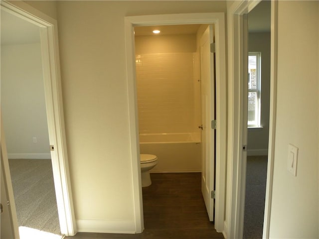 interior space featuring washtub / shower combination, wood-type flooring, and toilet