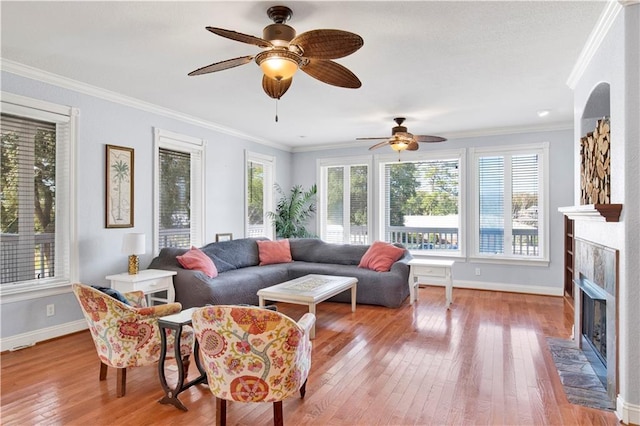 living room featuring a fireplace, light hardwood / wood-style flooring, ceiling fan, and ornamental molding