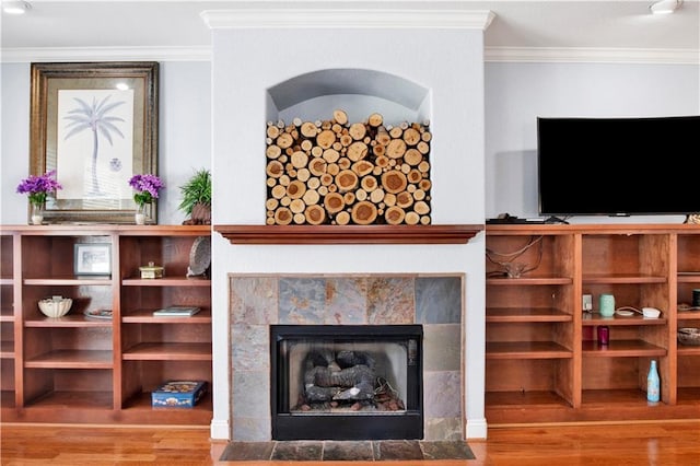 living room featuring a tiled fireplace, crown molding, and hardwood / wood-style flooring