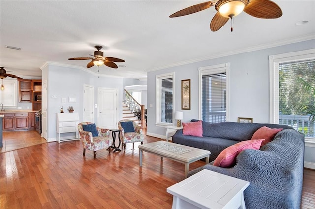 living room featuring hardwood / wood-style floors, ceiling fan, ornamental molding, and sink