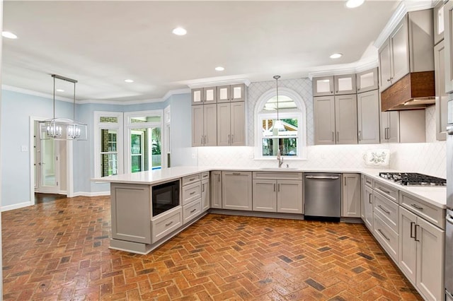 5555 Briarfield Ln, Mobile, AL 36693 - kitchen featuring stainless steel appliances, a peninsula, brick flooring, plenty of natural light, and crown molding