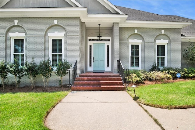 5555 Briarfield Ln, Mobile, AL 36693 - view of exterior entry featuring brick siding, a yard, and a shingled roof