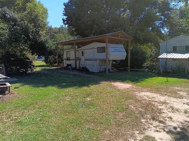 view of yard with dirt driveway and a carport
