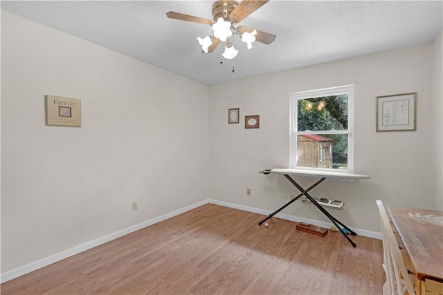 unfurnished office with light wood-style floors, ceiling fan, a textured ceiling, and baseboards