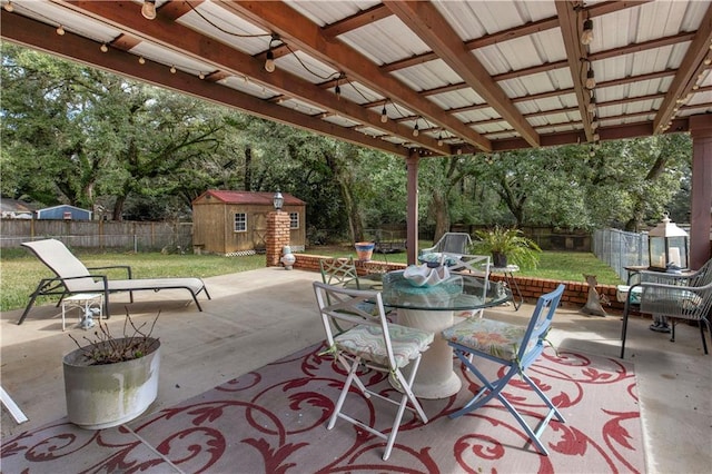 view of patio with an outbuilding, a storage unit, outdoor dining area, and a fenced backyard