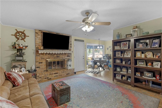 living room featuring a textured ceiling, a fireplace, crown molding, and ceiling fan with notable chandelier