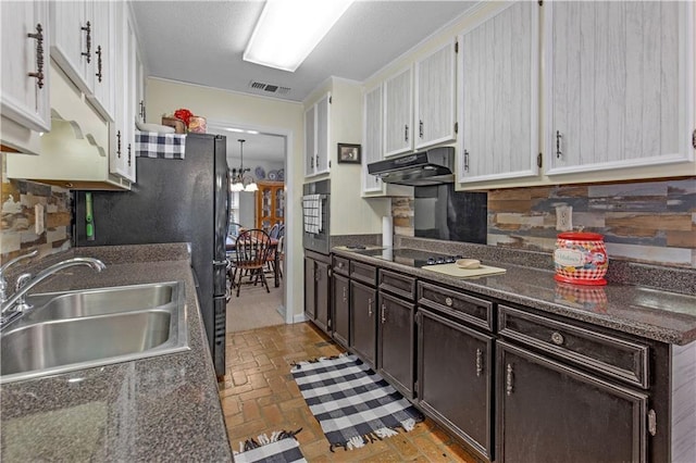 kitchen featuring dark countertops, oven, a sink, and under cabinet range hood