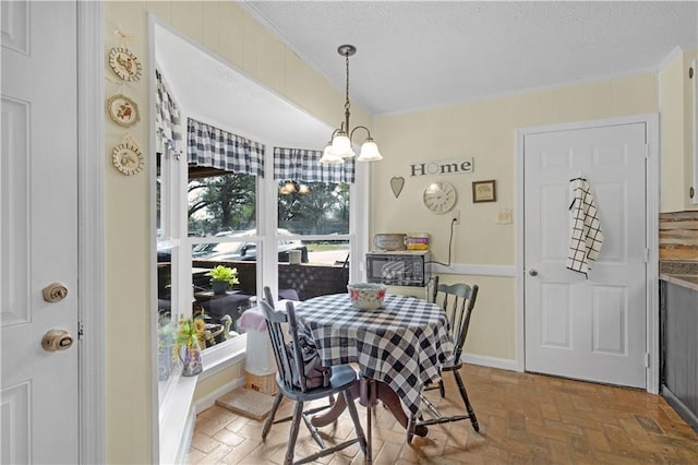 dining room with brick floor, a textured ceiling, baseboards, and an inviting chandelier