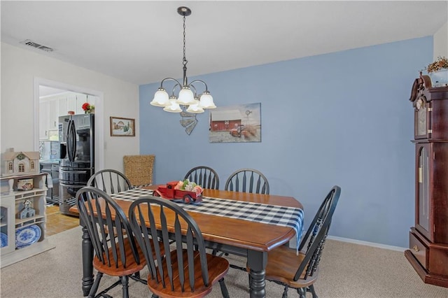 dining area featuring a chandelier, light colored carpet, visible vents, and baseboards