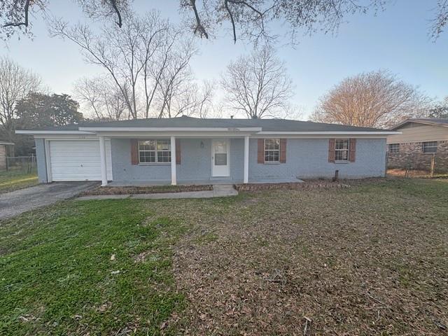 ranch-style home featuring a garage, aphalt driveway, a front yard, and fence