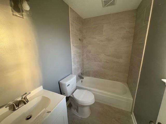 bathroom with visible vents, toilet, vanity,  shower combination, and tile patterned flooring