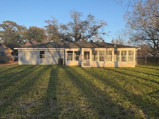 back of property with central air condition unit and a yard