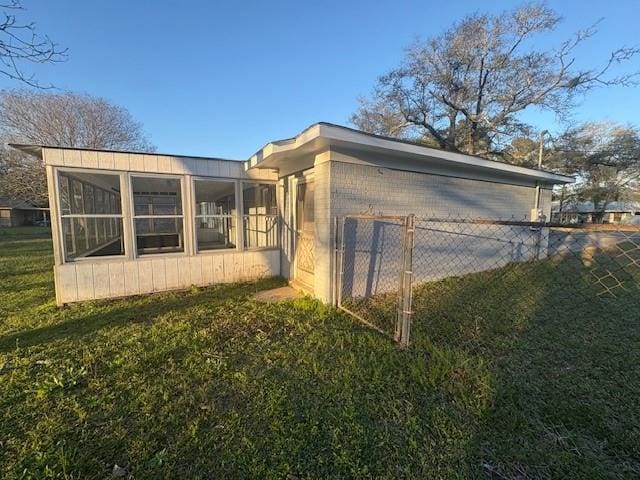 view of side of home with a yard, fence, and a sunroom