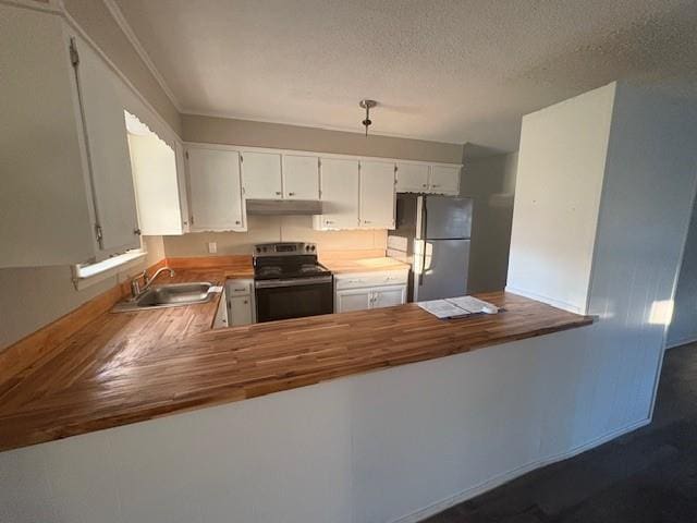 kitchen featuring freestanding refrigerator, a peninsula, a textured ceiling, black range with electric cooktop, and a sink