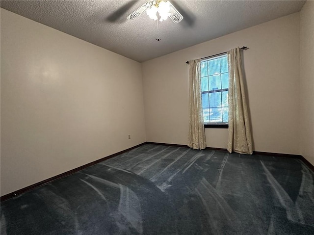 empty room featuring a textured ceiling, baseboards, a ceiling fan, and dark carpet