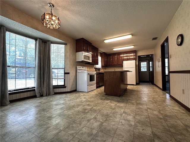 kitchen featuring a textured ceiling, a chandelier, visible vents, and white appliances