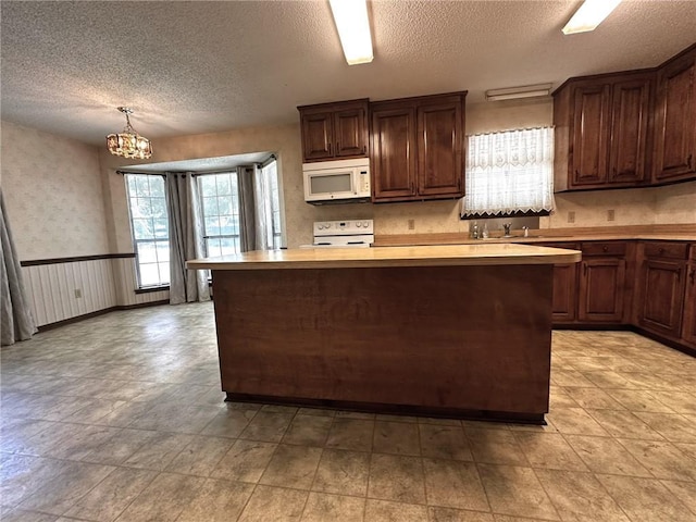 kitchen featuring a textured ceiling, white appliances, and light countertops