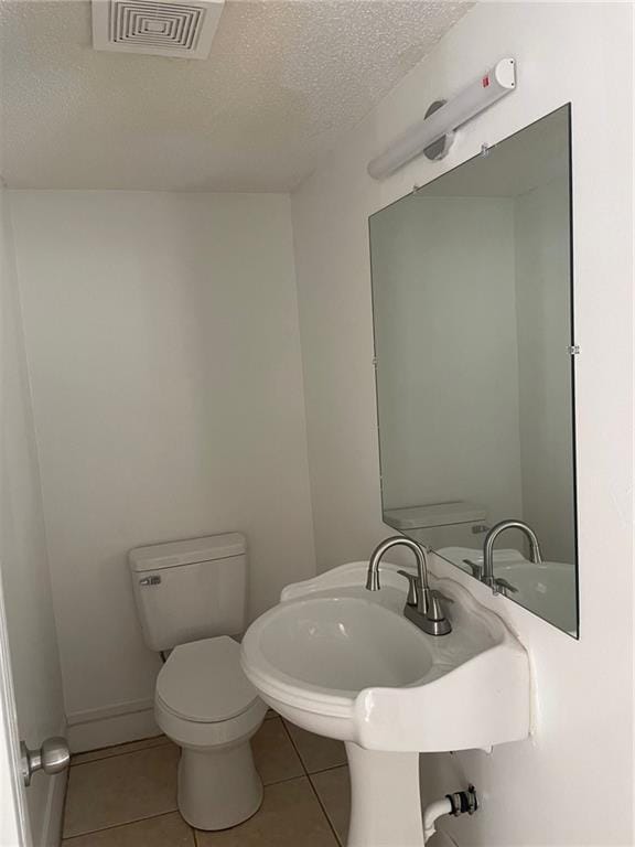 bathroom with tile patterned flooring, a textured ceiling, and toilet