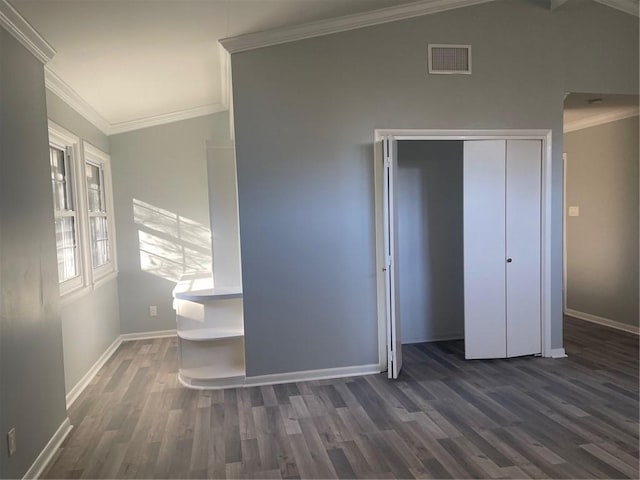 unfurnished bedroom featuring crown molding, dark hardwood / wood-style flooring, vaulted ceiling, and a closet