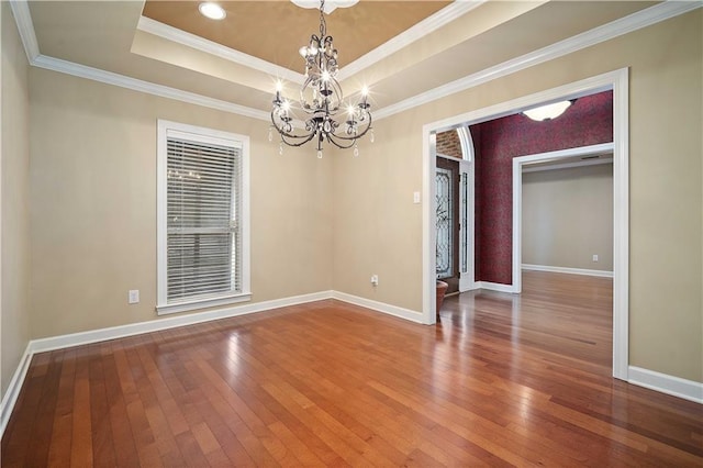 spare room featuring baseboards, a raised ceiling, a chandelier, and hardwood / wood-style flooring