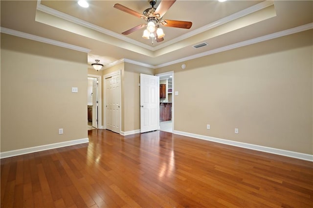 spare room with a raised ceiling, hardwood / wood-style flooring, visible vents, and ornamental molding