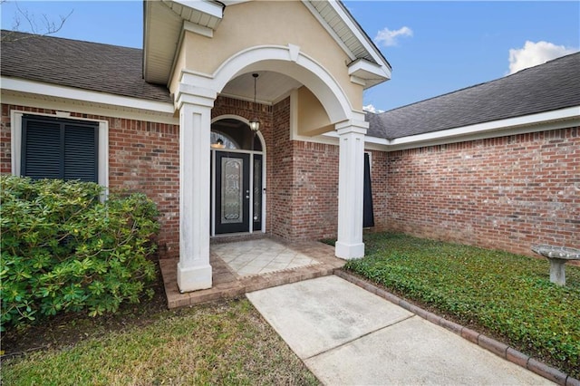 doorway to property with brick siding and roof with shingles