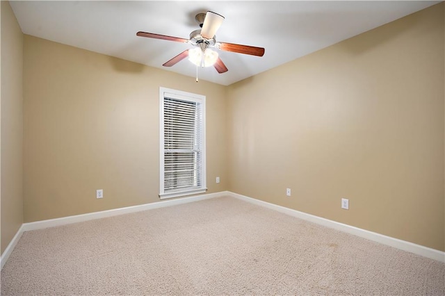 carpeted spare room featuring a ceiling fan and baseboards