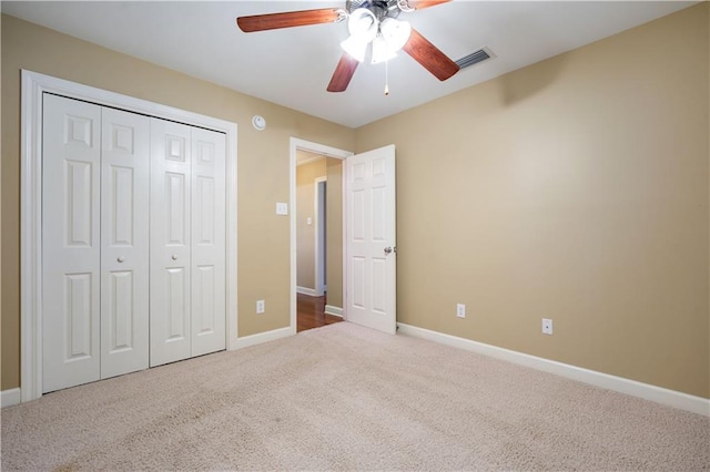 unfurnished bedroom with visible vents, a closet, carpet flooring, baseboards, and ceiling fan