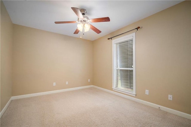 empty room with carpet flooring, a ceiling fan, and baseboards