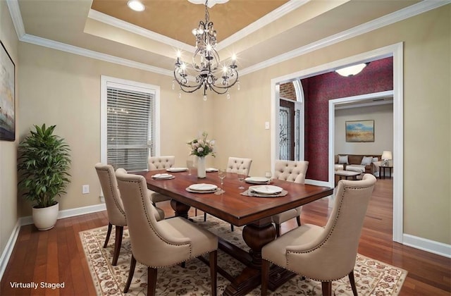 dining area with baseboards, a raised ceiling, an inviting chandelier, and wood-type flooring