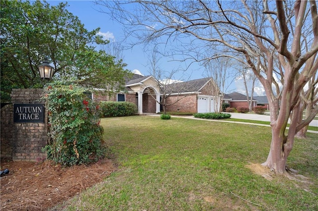 view of front of house with brick siding, a garage, driveway, and a front yard