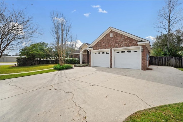 view of property exterior with brick siding, fence, a lawn, a garage, and driveway