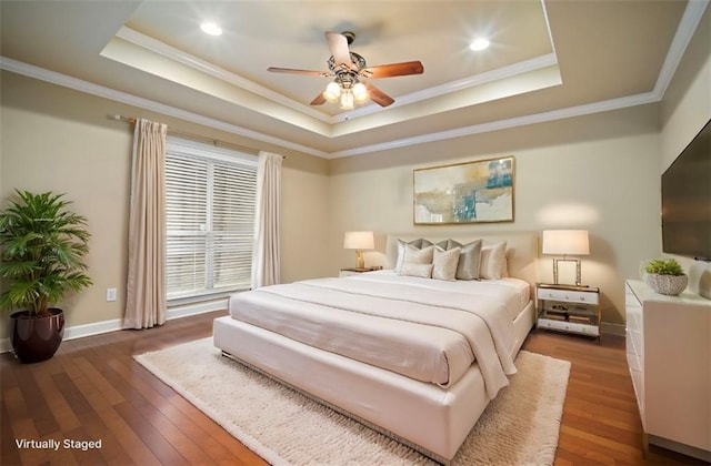 bedroom featuring ornamental molding, a tray ceiling, recessed lighting, wood-type flooring, and baseboards