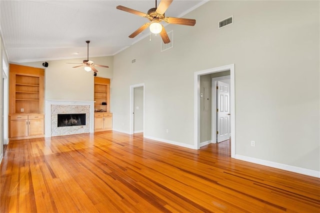 unfurnished living room with built in shelves, ceiling fan, high vaulted ceiling, and light hardwood / wood-style floors