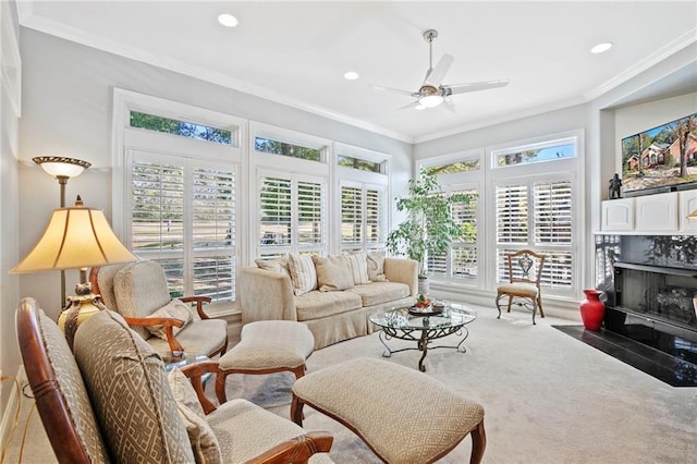 living room with ceiling fan, carpet, crown molding, and a fireplace