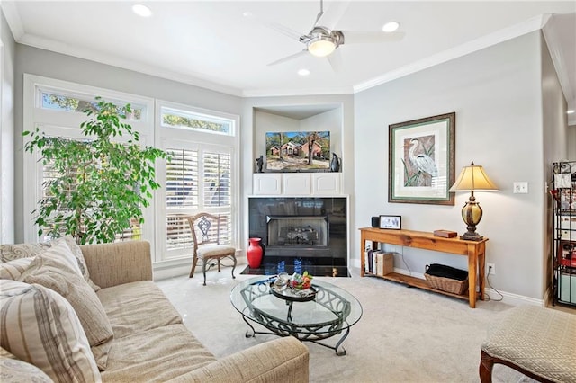 living room with ceiling fan, light colored carpet, ornamental molding, and a tiled fireplace