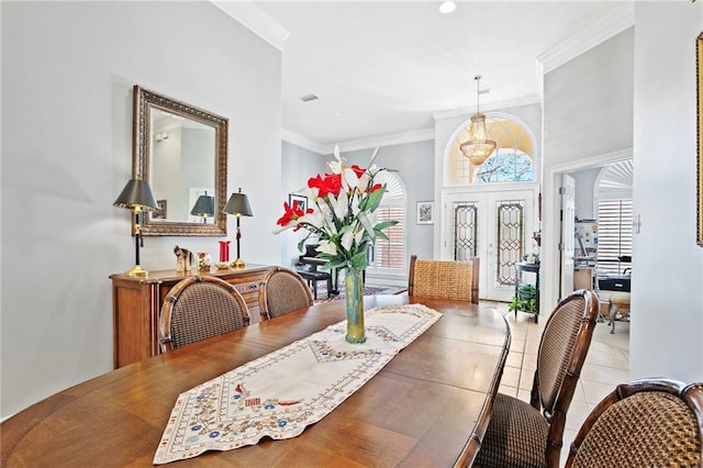 tiled dining room featuring french doors, a wealth of natural light, and ornamental molding