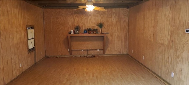 unfurnished room featuring wooden walls, ceiling fan, and light hardwood / wood-style floors