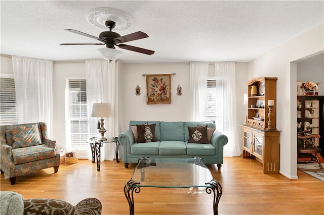 living room with a textured ceiling, light hardwood / wood-style floors, and ceiling fan