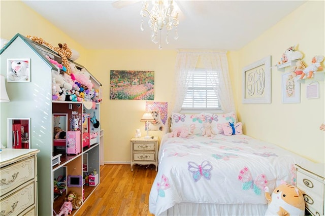 bedroom with ceiling fan with notable chandelier and light hardwood / wood-style flooring