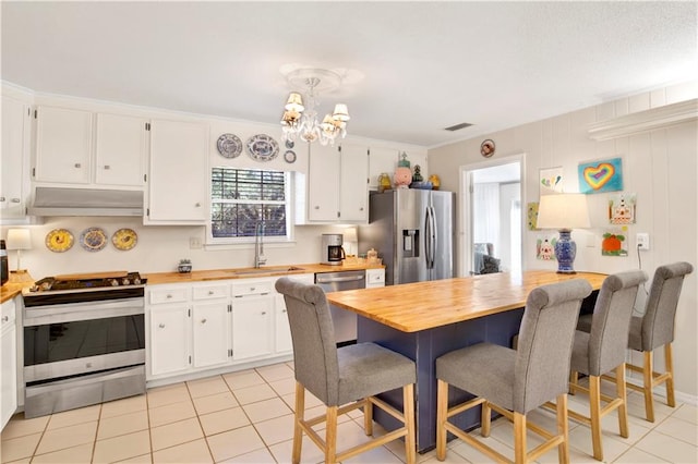 kitchen featuring butcher block counters, white cabinetry, sink, stainless steel appliances, and decorative light fixtures