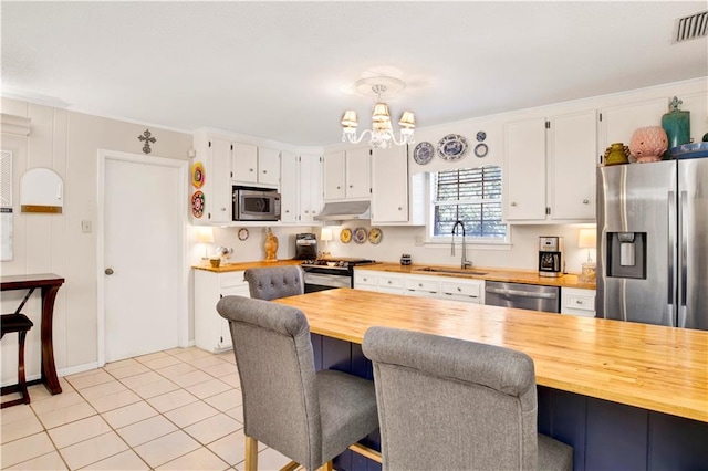 kitchen with pendant lighting, butcher block counters, and stainless steel appliances