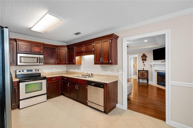 kitchen with ornamental molding, appliances with stainless steel finishes, sink, and a textured ceiling