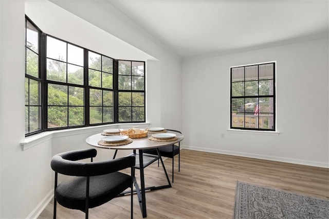 dining area with light wood-type flooring, ornamental molding, and a wealth of natural light