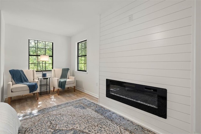 sitting room with a large fireplace, wood finished floors, and baseboards