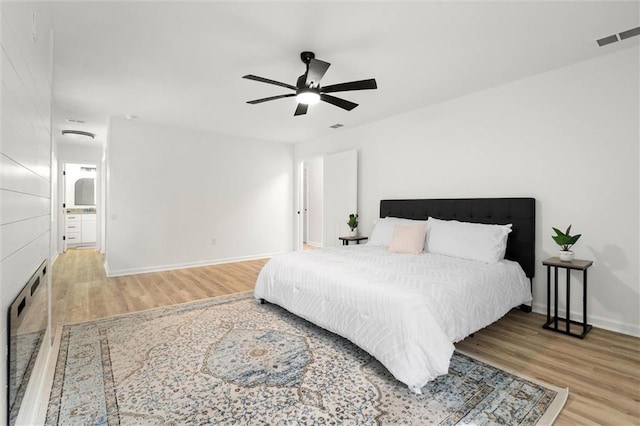 bedroom with a ceiling fan, visible vents, wood finished floors, and baseboards