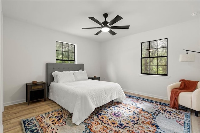 bedroom featuring baseboards, a ceiling fan, and light wood-style flooring