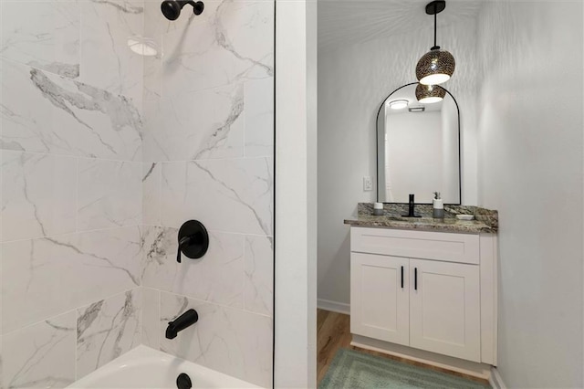 full bath featuring wood finished floors, vanity, and tub / shower combination