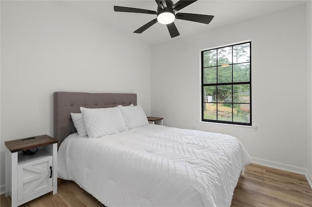 bedroom with wood finished floors, a ceiling fan, and baseboards