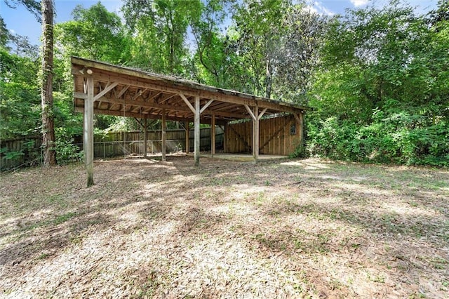view of car parking featuring an outbuilding, a carport, and fence